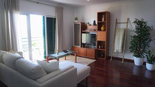 a living room with a white couch and a television at Villa Frente Mar by ESCAPE to Madeira in Funchal