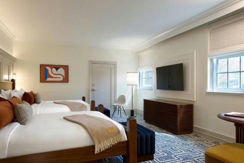 a hotel room with two beds and a flat screen tv at Dearborn Inn, Autograph Collection in Dearborn