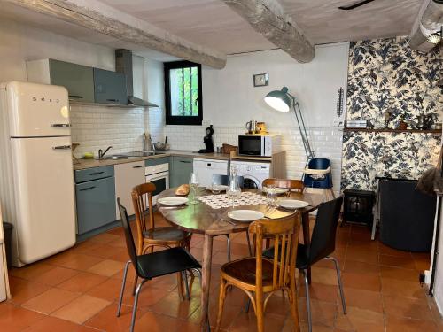 une cuisine avec une table, des chaises et un réfrigérateur dans l'établissement Maison cosy en Provence Proche Golf Pont Royal, à Alleins
