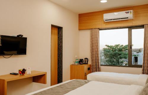 a hotel room with two beds and a window at Daksh The Grand Goverdhan in Dwarka