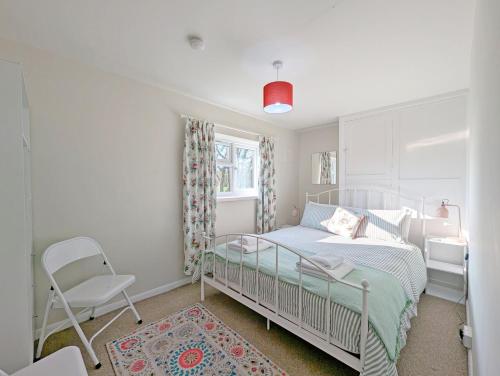 Un pequeño dormitorio con una cama y una silla. en Southwood Farm Cottage, en West Stoke