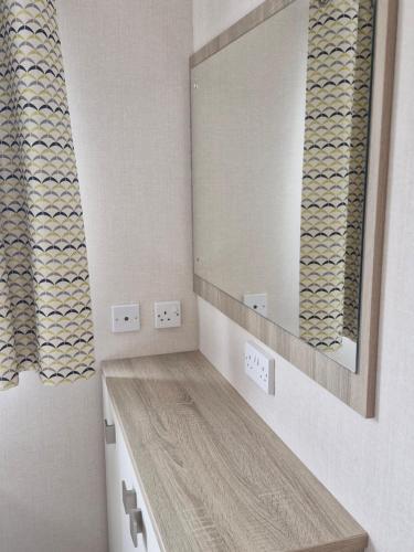 ein Badezimmer mit Waschbecken und großem Spiegel in der Unterkunft The Lodge at Hafan Church Bay, Gadlys Coastal Cottages in Llanrhyddlad