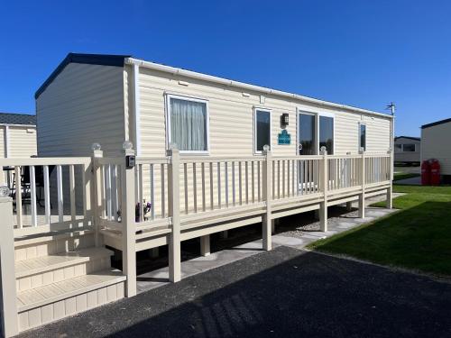 a mobile home with a porch and a fence at PG174 Golden Palm Resort 8 Berth Caravan With Decking in Chapel Saint Leonards