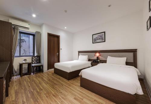 a hotel room with two beds and a desk at Collection O Le Grand Hanoi hotel - The Tryst in Hanoi