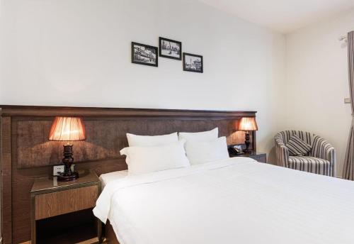 a bedroom with a bed and two lamps and a chair at Collection O Le Grand Hanoi hotel - The Tryst in Hanoi