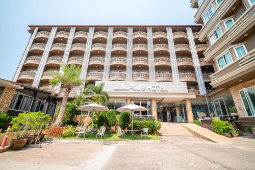 Un edificio con mesas y sombrillas delante. en Sunday JA Plus Hotel, en Pattaya central