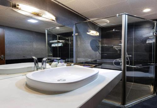 a bathroom with a sink and a glass shower at Collection O Le Grand Hanoi hotel - The Tryst in Hanoi