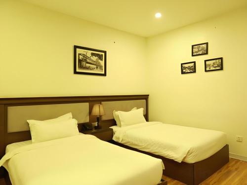 a hotel room with two beds and pictures on the wall at Collection O Le Grand Hanoi hotel - The Tryst in Hanoi