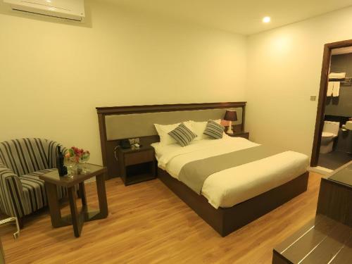 a bedroom with a bed and a couch and a chair at Collection O Le Grand Hanoi hotel - The Tryst in Hanoi
