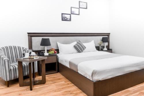a bedroom with a large bed and a chair at Collection O Le Grand Hanoi hotel - The Tryst in Hanoi