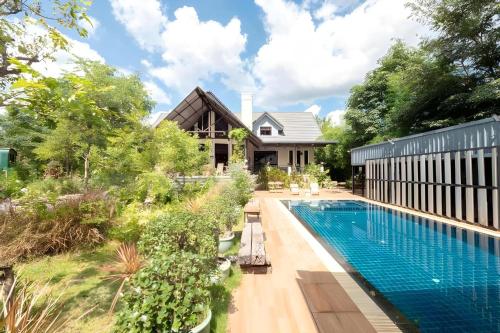 an image of a swimming pool in front of a house at Capital O 75378 Thawapee Resort in Rayong