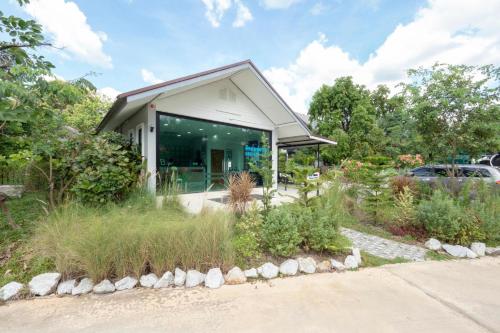 a house with a glass door in a garden at Capital O 75378 Thawapee Resort in Rayong