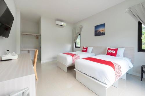 a bedroom with two beds with red and white sheets at Capital O 75378 Thawapee Resort in Rayong