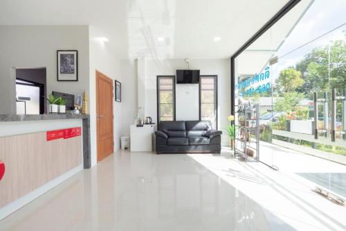 a living room with a black leather couch in a building at Capital O 75378 Thawapee Resort in Rayong