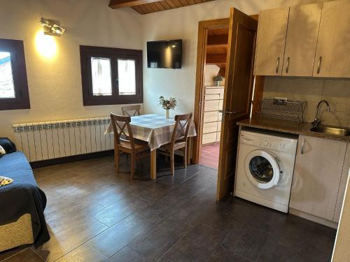 a living room with a table and a washing machine at Hotel Rural L'Ortiga Blanca in Queralbs