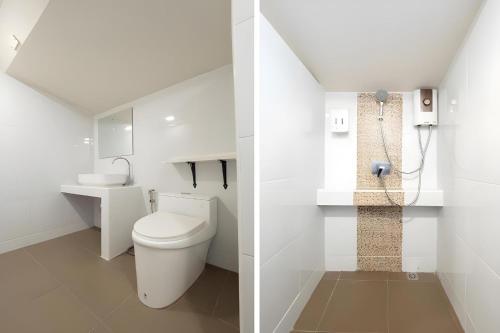 a white bathroom with a toilet and a shower at Capital O 75378 Thawapee Resort in Rayong
