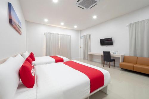 a hotel room with two beds and a desk at Capital O 75378 Thawapee Resort in Rayong