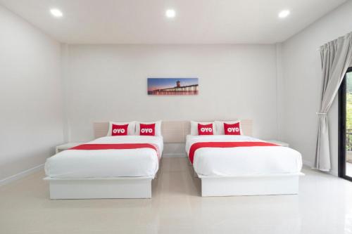 two beds in a white room with a bridge at Capital O 75378 Thawapee Resort in Rayong