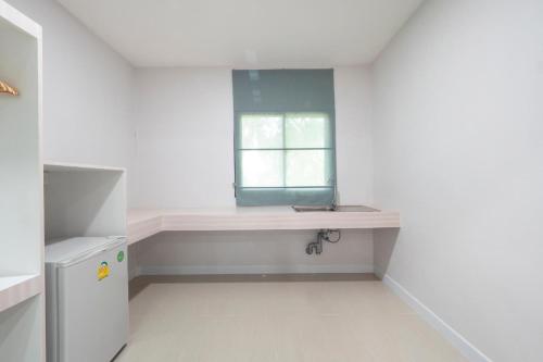 a white kitchen with a window and a sink at Capital O 75378 Thawapee Resort in Rayong