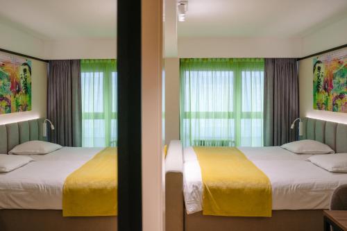 two beds in a hotel room with windows at Ostend Hotel in Ostend