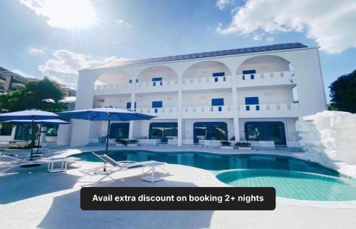 un grand bâtiment blanc avec une piscine et des parasols dans l'établissement Collection O To The Sea Resort Thailand, à Na Jomtien