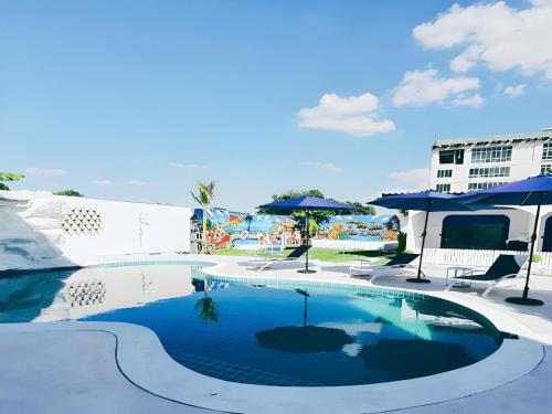 a swimming pool with blue umbrellas and chairs at Collection O To The Sea Resort Thailand in Na Jomtien