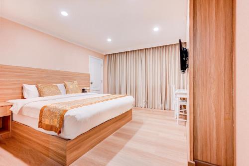 a hotel room with a large bed and a television at Palette The Travellers Hotel Bangkok in Bangkok