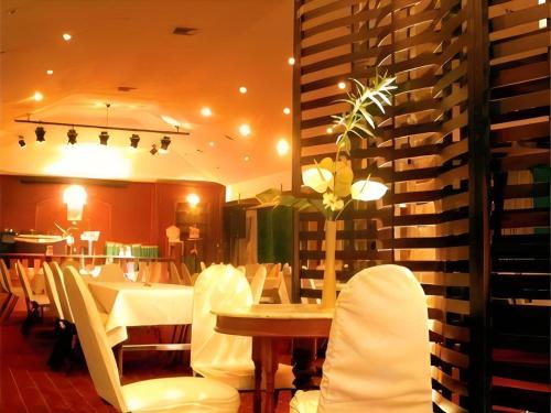 a dining room with a table and white chairs at Palette The Travellers Hotel Bangkok in Bangkok