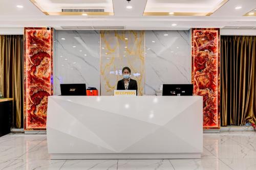 a man standing behind a counter in a room with two laptops at Palette The Travellers Hotel Bangkok in Bangkok