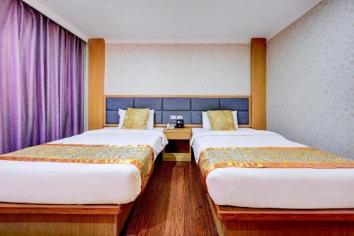 two beds in a room with purple curtains at Palette The Travellers Hotel Bangkok in Bangkok