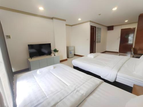 a hotel room with two beds and a flat screen tv at OYO 75446 Travis Inthamara 49 in Bangkok