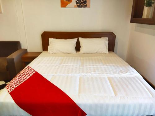 a bed with a red and white blanket on it at OYO 75446 Travis Inthamara 49 in Bangkok