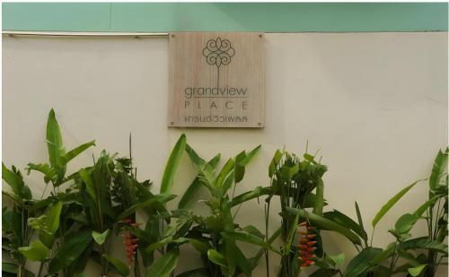 a sign hanging on a wall next to plants at Grandview Place in Bangkok