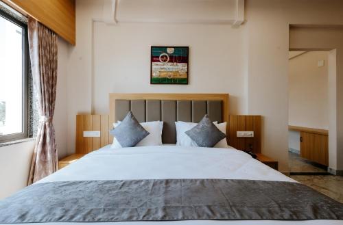 a bedroom with a large white bed with blue pillows at Daksh The Grand Goverdhan in Dwarka