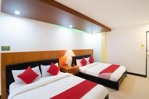 two beds in a hotel room with red and white pillows at OYO 195 Ranchotel - Biñan in Biñan