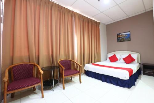 a hotel room with a bed and two chairs at Hotel O Destiny Riverside Hotel in Kota Bharu