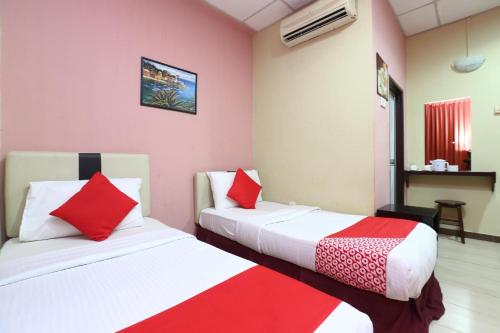 two beds in a room with red and white at Hotel O Destiny Riverside Hotel in Kota Bharu