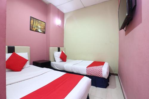 a room with two beds with red and white sheets at Hotel O Destiny Riverside Hotel in Kota Bharu