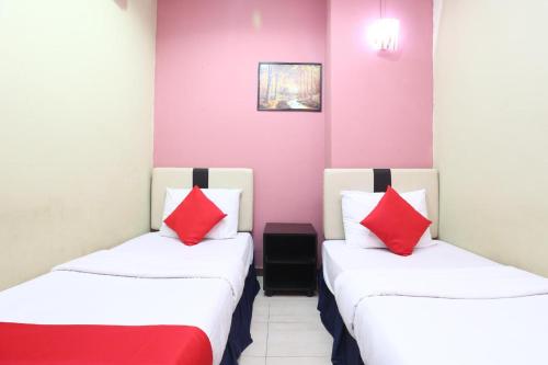 two beds in a room with red and white pillows at Hotel O Destiny Riverside Hotel in Kota Bharu