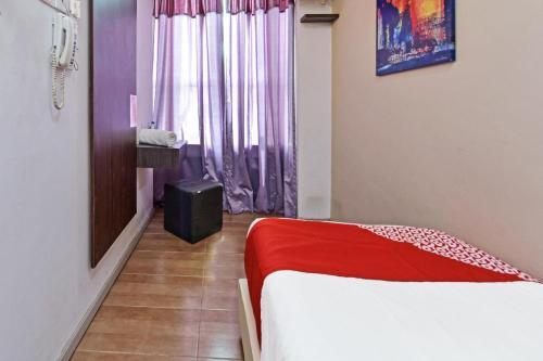 a room with a bed with a red blanket and a window at Hotel O Fajar Baru Boutique Hotel in Kuala Terengganu