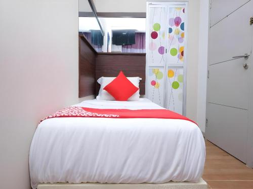 a bedroom with a white bed with a red pillow at Hotel O Fajar Baru Boutique Hotel in Kuala Terengganu