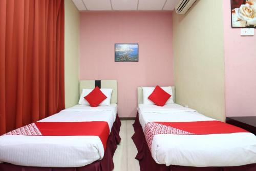 two beds in a room with red curtains at Hotel O Destiny Riverside Hotel in Kota Bharu