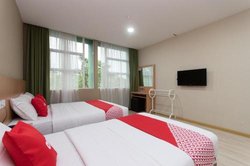 a hotel room with two beds and a television at Capital O 89344 Labuan Avenue Hotel in Labuan