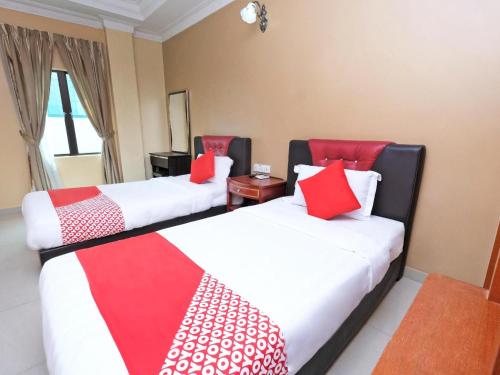 two beds in a room with red and white pillows at Hotel O Ayuni Hotel in Bangi