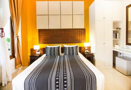a bedroom with a large bed with an orange wall at Sunday Telaga Terrace Boutique Resort in Pantai Cenang