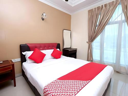 a bedroom with a bed with red pillows and a window at Hotel O Ayuni Hotel in Bangi
