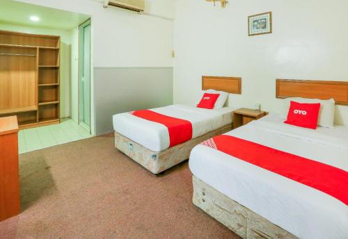 two beds in a hotel room with red pillows at Hotel O My Hotel in Segamat