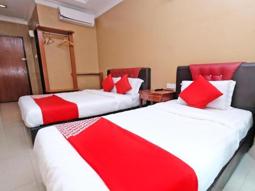 two beds in a hotel room with red pillows at Hotel O Ayuni Hotel in Bangi