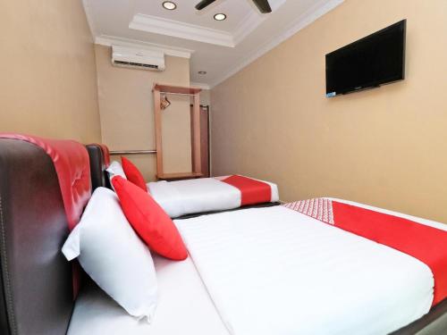 a room with two beds with red and white pillows at Hotel O Ayuni Hotel in Bangi