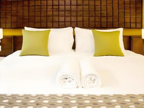 a bed with white sheets and green pillows at Sunday Telaga Terrace Boutique Resort in Pantai Cenang